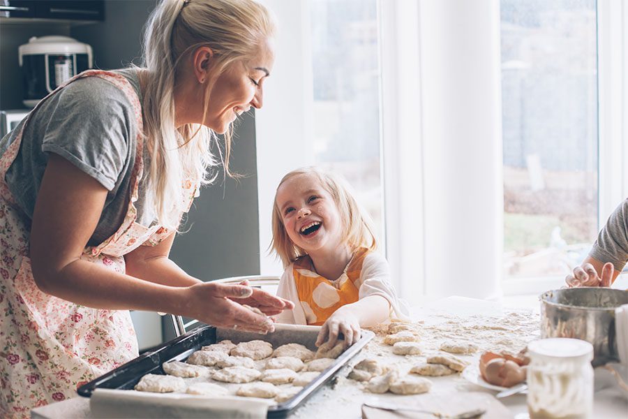 Client Center - View of a Cheerful Grandmother and Granddaughter Having Fun Together While Cooking Together in the Kitchen