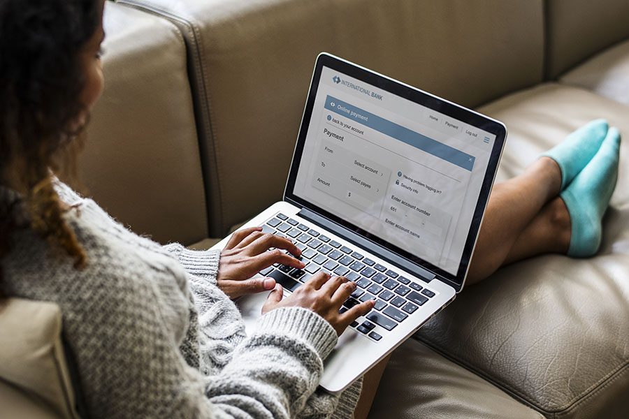 General Service Request - Portrait of a Young Woman in a Warm Sweater Sitting on a Sofa at Home While Working on Her Laptop